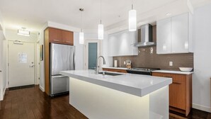 Uma cozinha moderna com ilha central, eletrodomésticos de aço inoxidável e iluminação pendente.