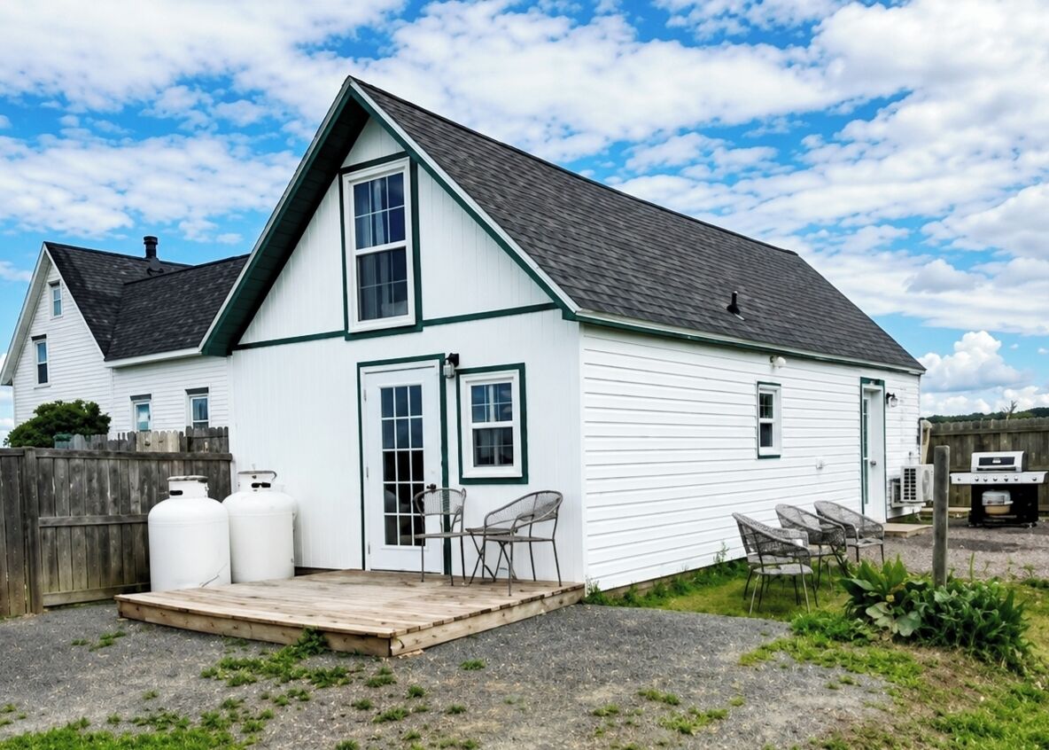 A two-story house with a front porch, a garage, and a barbecue grill in the backyard.