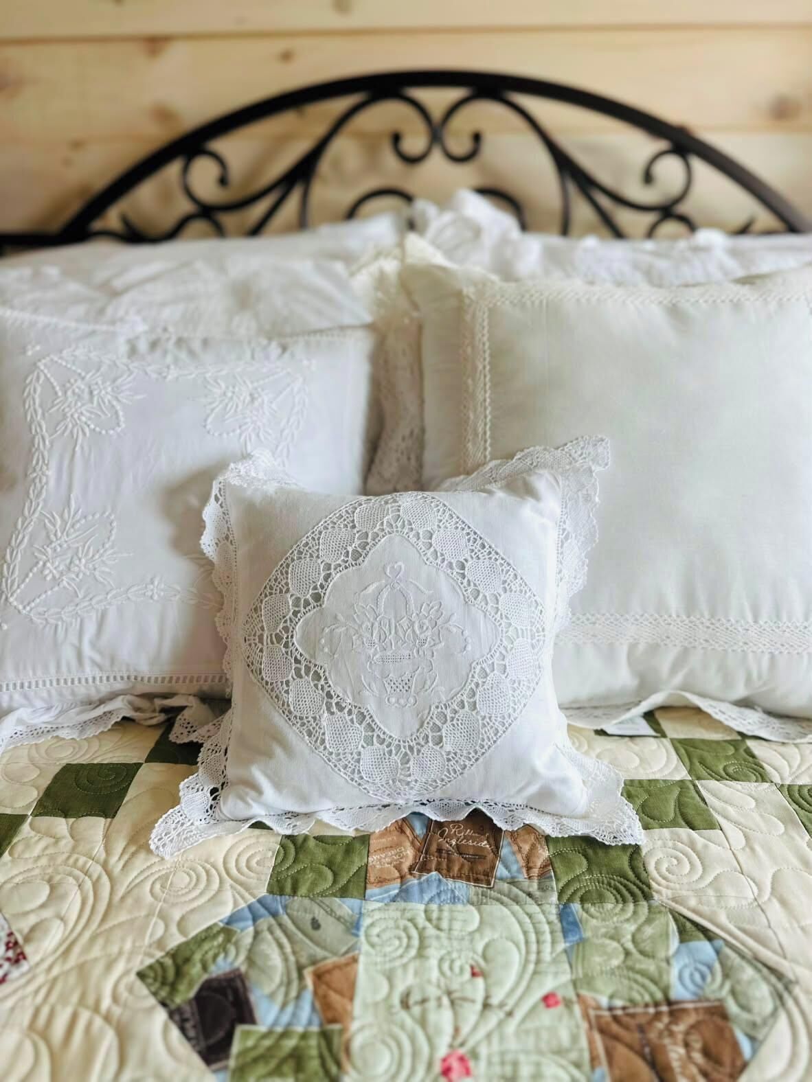 Ein Bett mit einer gesteppten Tagesdecke und drei Kissen mit Spitzenbesatz.