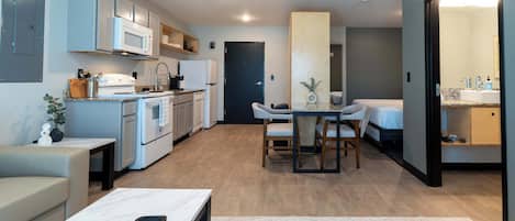Un espacio habitable compacto con kitchenette, comedor y un dormitorio.