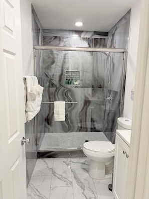 A bathroom with a glass-enclosed shower, a toilet, and a sink. - Beautiful luxury apartment just 10 minutes from The Strip (Las Vegas)