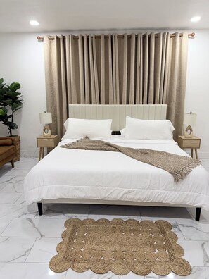 A neatly made bed with white linens, a beige throw blanket, and a woven rug on a marble floor. - Beautiful luxury apartment just 10 minutes from The Strip (Las Vegas)