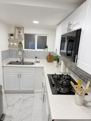 A modern kitchen with white cabinets, a black stove, and a microwave. - Beautiful luxury apartment just 10 minutes from The Strip (Las Vegas)