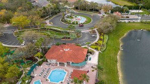 A resort with a swimming pool, a covered pavilion, and a lake. - Whimsical Couple's Escape: Minutes to Disney (Kissimmee)