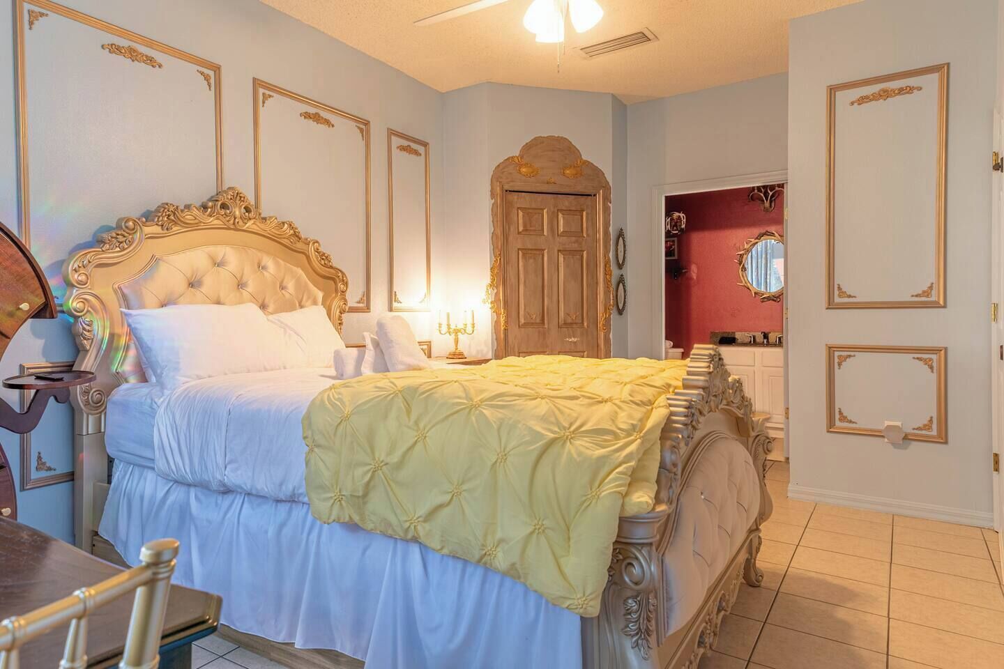 A bedroom with a large bed, a wooden door, and a mirror on the wall.