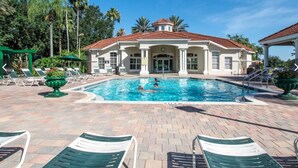 A swimming pool with lounge chairs and a building with a red-tiled roof. - Whimsical Couple's Escape: Minutes to Disney (Kissimmee)