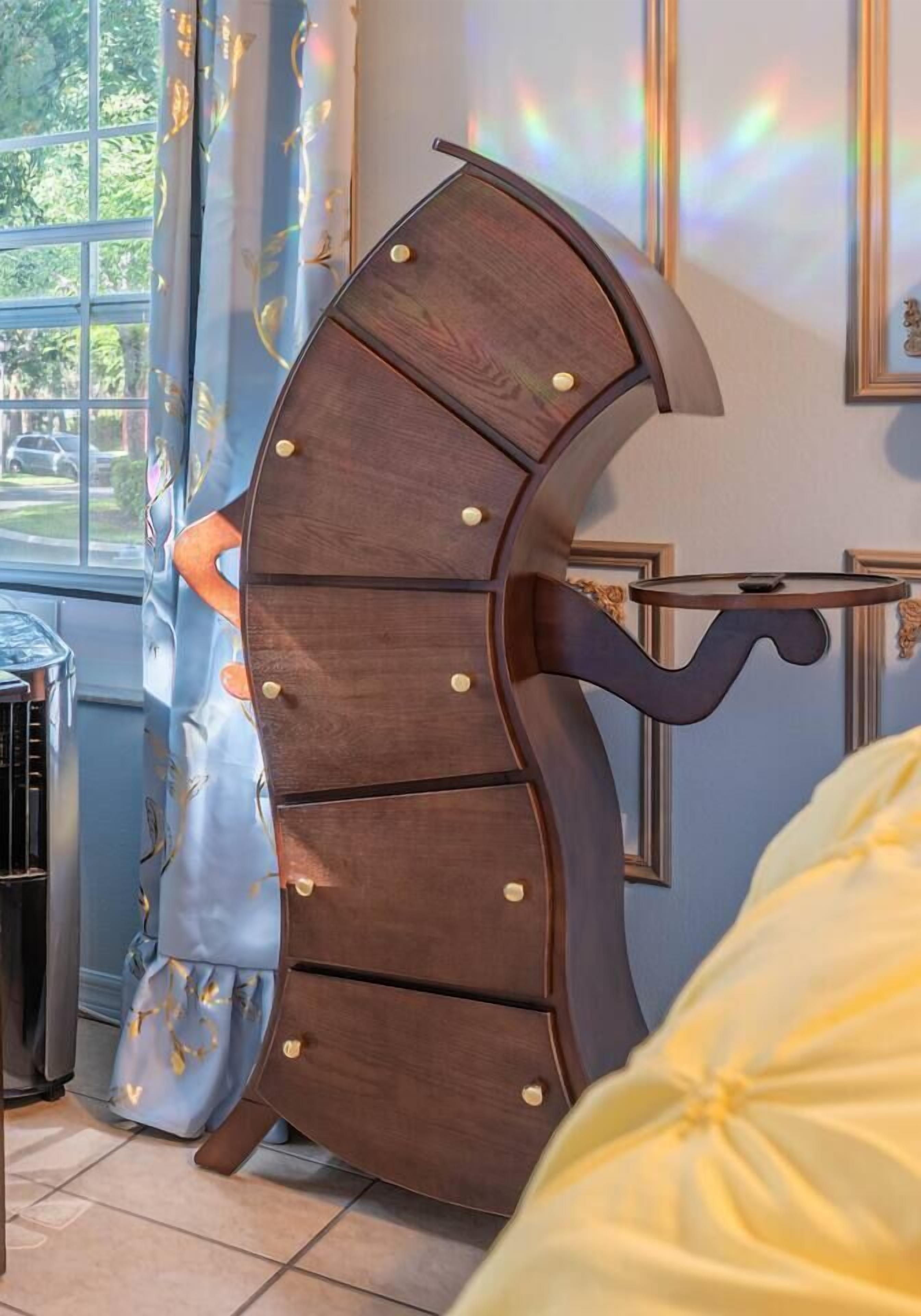 Ein Zimmer mit einem geschwungenen Möbelstück aus Holz, einem kleinen Tisch und einem Fenster mit Vorhängen.