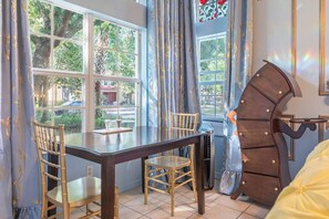 A dining area with a table, chairs, and a view of the outdoors through large windows. - Whimsical Couple's Escape: Minutes to Disney (Kissimmee)