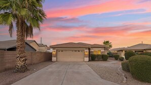 A residential area with a single house featuring a garage, a driveway, and a well-maintained lawn. - Oasis on Aubrac | Modern 5BR | Private Pool | Pergola & Firepit | Sleeps 8 (San Tan Valley)