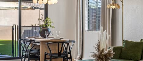 Un comedor con una mesa, sillas y un jarrón de flores.