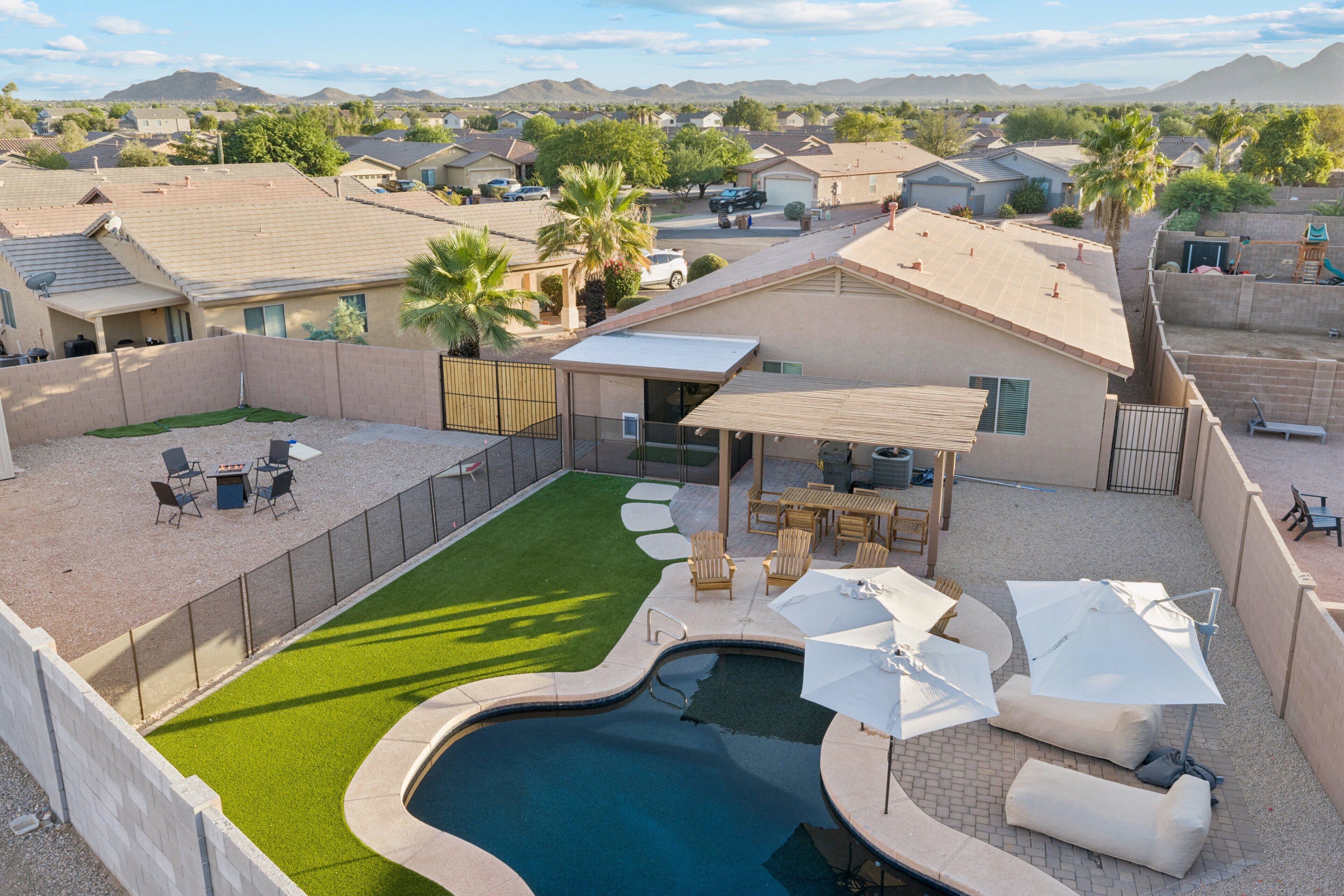 A residential backyard with a swimming pool, patio furniture, and a covered seating area.