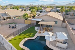 Un cortile residenziale con piscina, mobili da patio e una zona relax coperta.