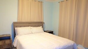 Ein Schlafzimmer mit einem Bett, Nachttischen und Vorhängen.