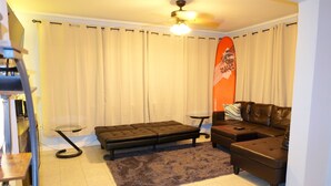 Ein Wohnzimmer mit einer Couch, einem Zweisitzer, einem kleinen Tisch, einer Stehlampe und einem Deckenventilator.
