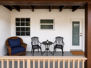 A porch with a wicker chair, two metal chairs, a small table, and a door. - Coconut Grove Area - Modern Home - Sleeps 6 (Miami)