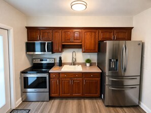 A modern kitchen with stainless steel appliances, wooden cabinets, and a built-in microwave. - Coconut Grove Area - Modern Home - Sleeps 6 (Miami)