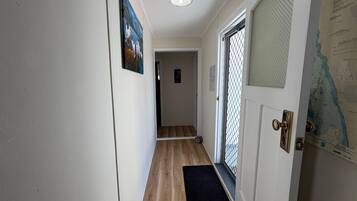 A hallway with a wooden floor, a door with a metal gate, and a wall with a map.