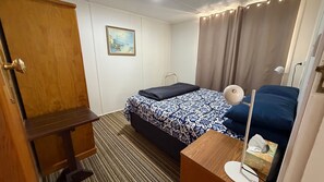 Een hotelkamer met een bed, een bureau, een stoel, een lamp en een schilderij aan de muur.