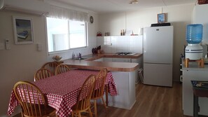 Una cocina compacta con comedor, que incluye una mesa con sillas, un refrigerador y un dispensador de agua.