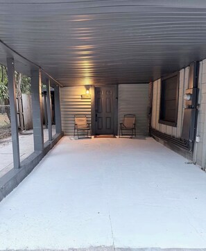Eine Garage mit Betonboden, zwei Stühlen, einer Tür und einem 'WELCOME'-Schild.