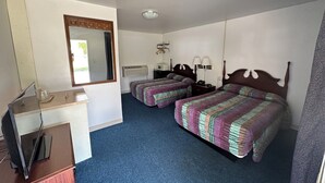 Hotellihuone, jossa on kaksi sänkyä, työpöytä, peili, ilmastointilaite ja kattotuuletin.