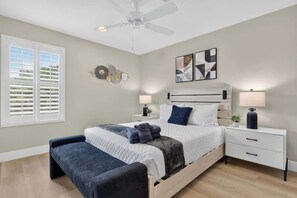 Ein Schlafzimmer mit einem Bett, Nachttischen, einer Bank, einem Deckenventilator und Bildern an der Wand.