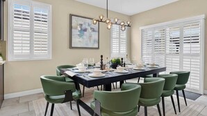 Comedor con una mesa rectangular dispuesta para seis personas, rodeada por seis sillas verdes.