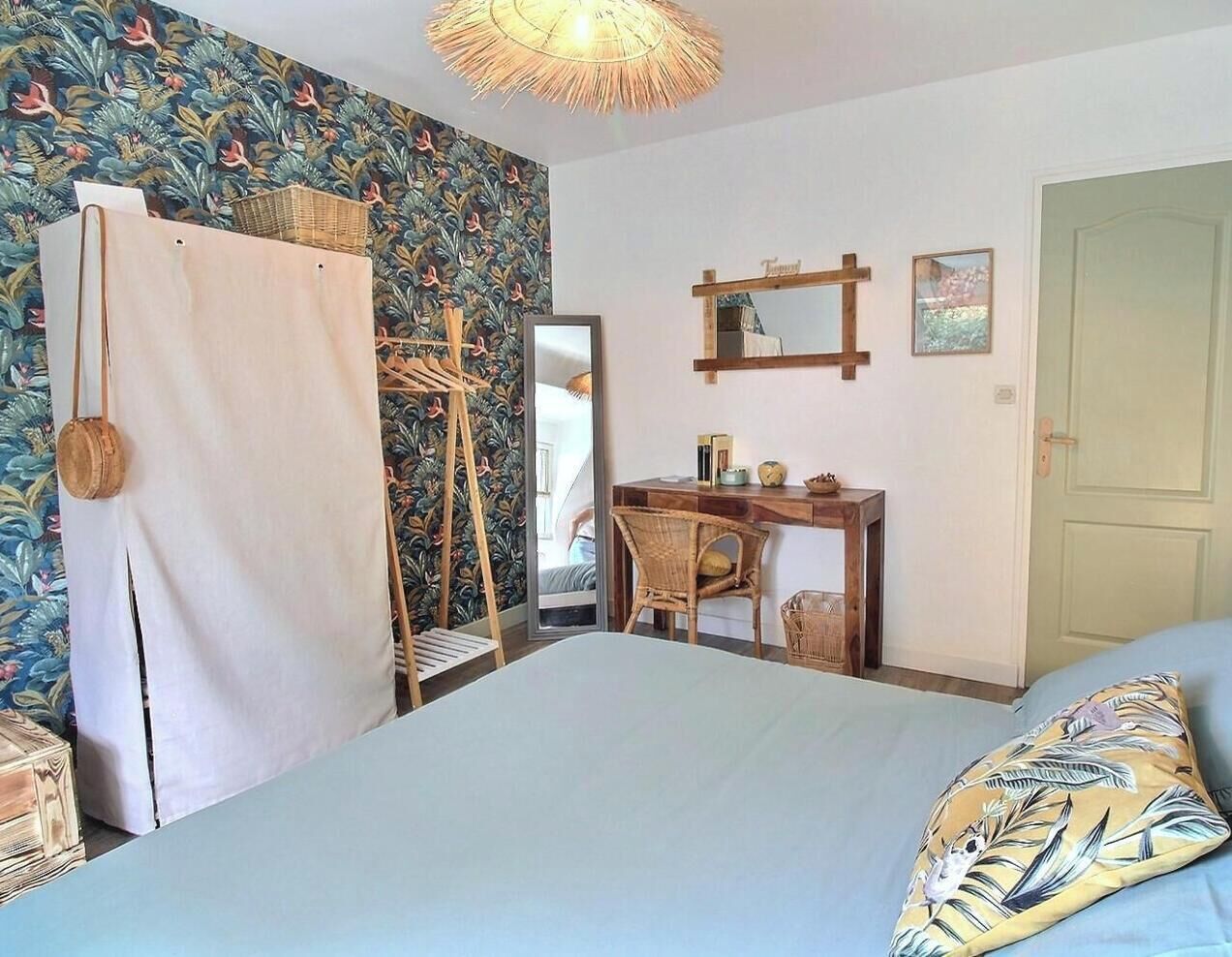 Une chambre à coucher comprenant un lit, un bureau, une chaise, une armoire et un miroir.