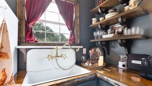 A vintage kitchen with a white sink, wooden shelves with dishes, and a coffee maker. - The Stargazer Cabin - A Hill Country Retreat (Fredericksburg)