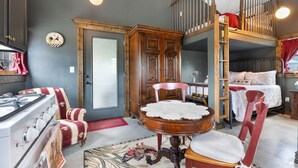 A room with a bunk bed, a wooden cabinet, a stove, and a round table with a lace tablecloth. - The Stargazer Cabin - A Hill Country Retreat (Fredericksburg)