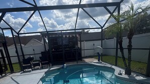 Una piscina con idromassaggio, circondata da un patio coperto con sedie e un barbecue.