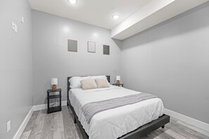 A bedroom with a bed, bedside tables, and wall-mounted light fixtures.
