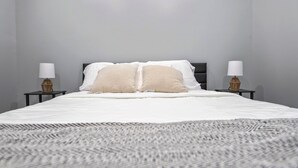Un dormitorio con una cama, dos mesitas de noche y tres cuadros colgados en la pared.