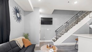 Una sala de estar moderna con un sofá, una mesa de centro y una escalera que lleva a un nivel superior.