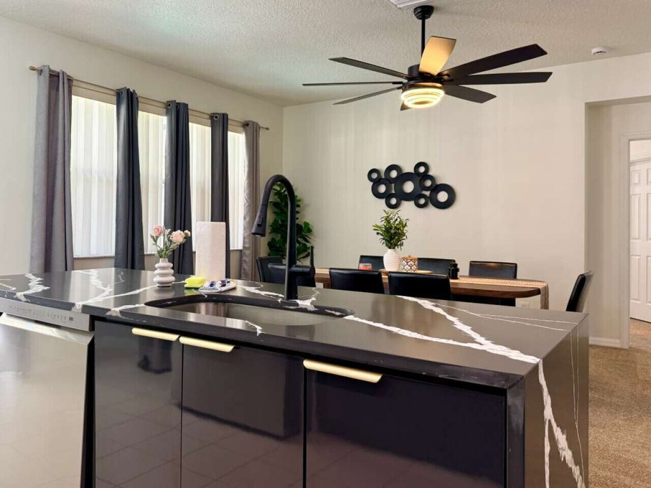 A modern kitchen with a black countertop, a built-in sink, and a ceiling fan.