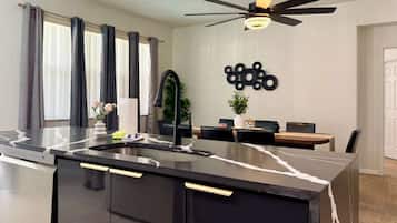 A modern kitchen with a black countertop, a built-in sink, and a ceiling fan.