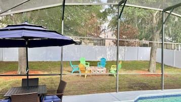 A covered outdoor area with a pool, seating, and a fire pit.