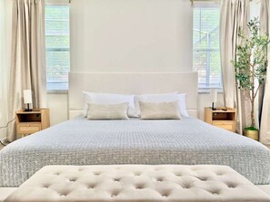 A bedroom with a large bed, two bedside tables, a nightstand, and a potted plant. - Stunning 4BR Pool Home: Your Private Oasis Awaits! (Davenport)