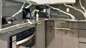 Una cocina moderna con salpicadero de mármol, electrodomésticos de acero inoxidable y muebles de cocina blancos.