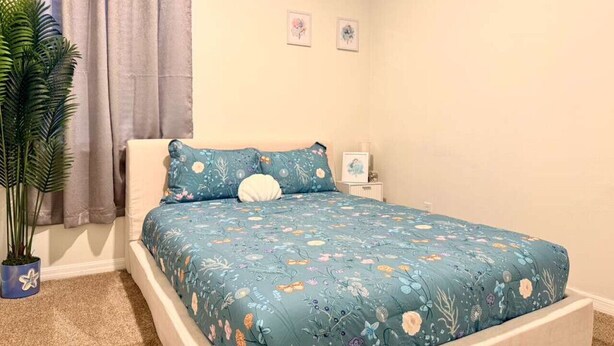 Un dormitorio con cama, una planta en maceta y una ventana con cortinas.