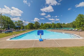 Ein rechteckiger Swimmingpool mit einem blauen Sprungbrett in der Mitte, umgeben von einer Betonplattform.