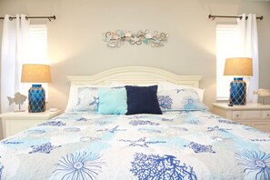 Ein Schlafzimmer mit einem Bett, zwei Nachttischen, einer Wanddekoration und Vorhängen.