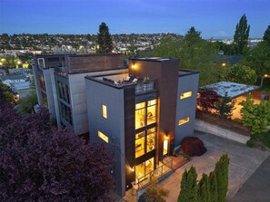 Ein modernes Gebäude mit flachem Dach, großen Fenstern und einem Balkon mit Sitzgelegenheit.
