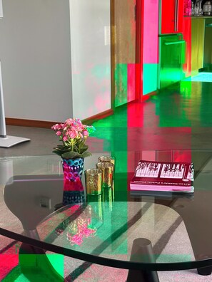 Ein Glastisch mit einer Vase voller rosa Blumen, einem Stapel Bücher und einem Glas Wasser.