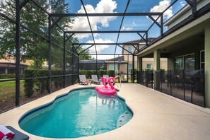 A swimming pool with a glass enclosure, lounge chairs, and a flamingo float. - PROMO read below-Near Disney -Private POOL (Davenport)