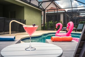 Un décor de bord de piscine avec un verre à cocktail, des chaises longues et des flamants roses gonflables.