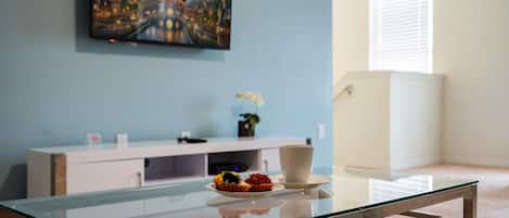 Una habitación con una mesa de vidrio, un armario blanco y un cuadro de un castillo en la pared.