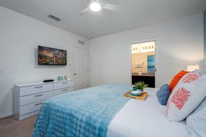 A bedroom with a bed, a dresser, a painting, and a bathroom visible through an open door. - Sunset Swims & Disney Dreams-Modern Family Oasis (Davenport)