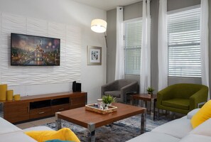 A living room with a sofa, a coffee table, a TV, a fireplace, and a window with blinds. - PROMO read below-Near Disney -Private POOL (Davenport)