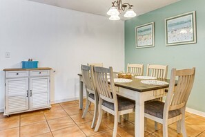Uma sala de jantar com mesa, cadeiras, um armário e obras de arte nas paredes.